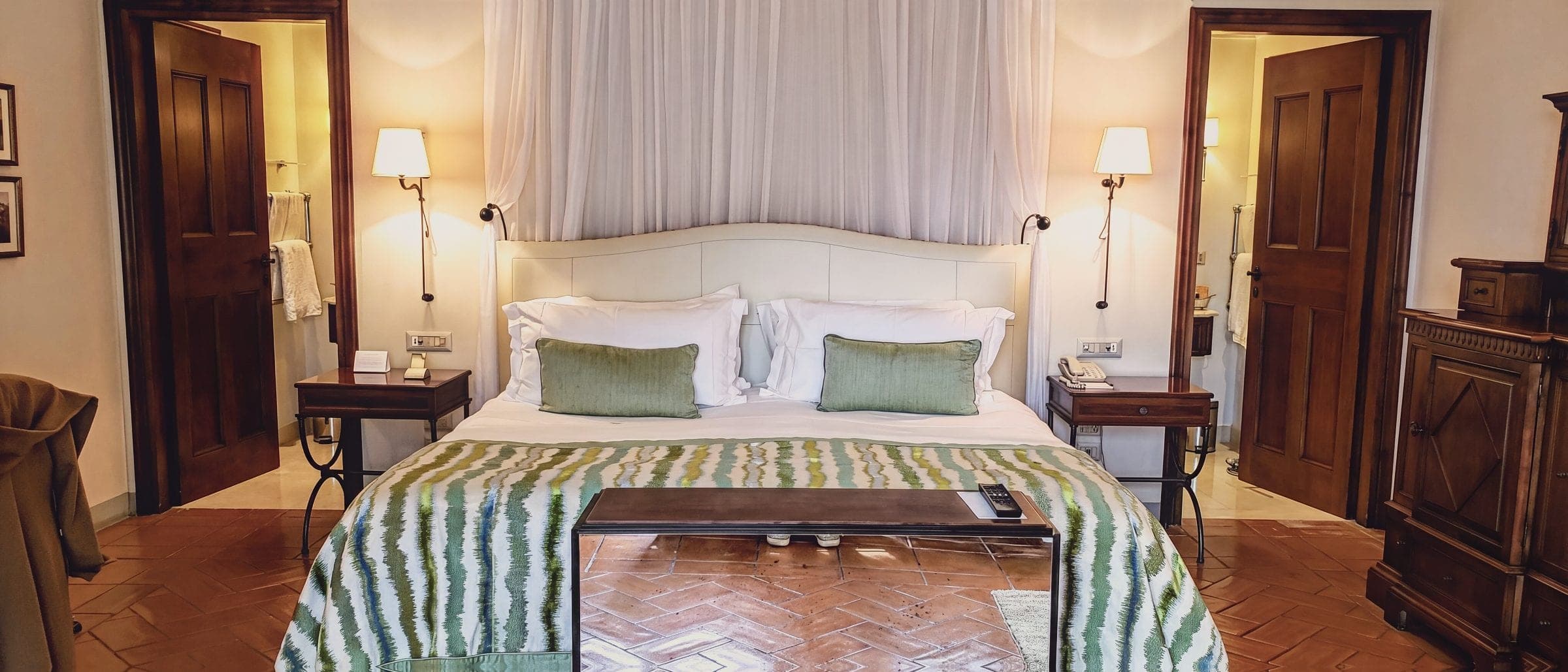 A guest room with a striped bedspread, wooden doors and antique furniture