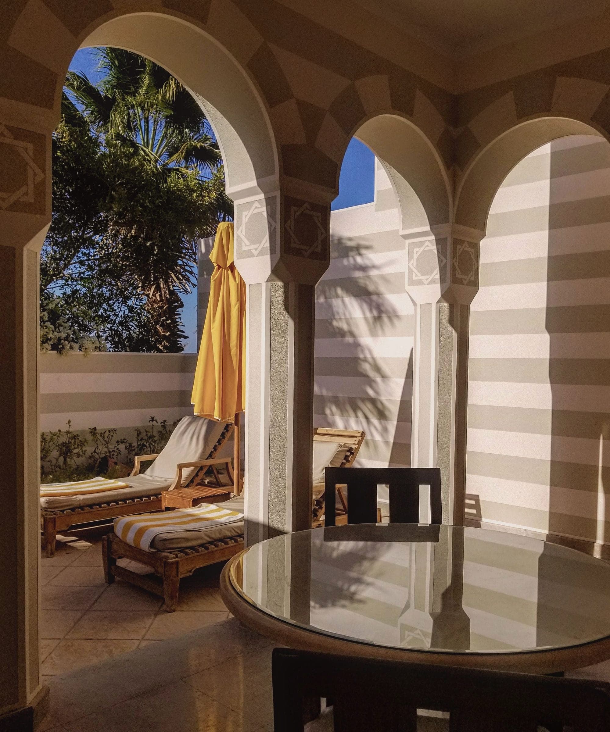 A shaded terrace behind white arches at The Oberoi Sahl Hasheesh