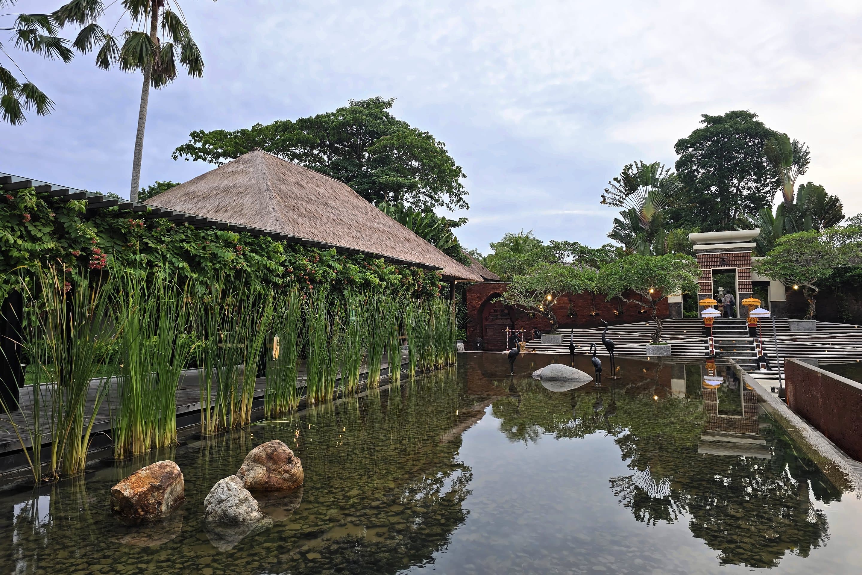 A reflecting pool, thatched pavilion and stone temple gate at a resort in Bali, Indonesia.