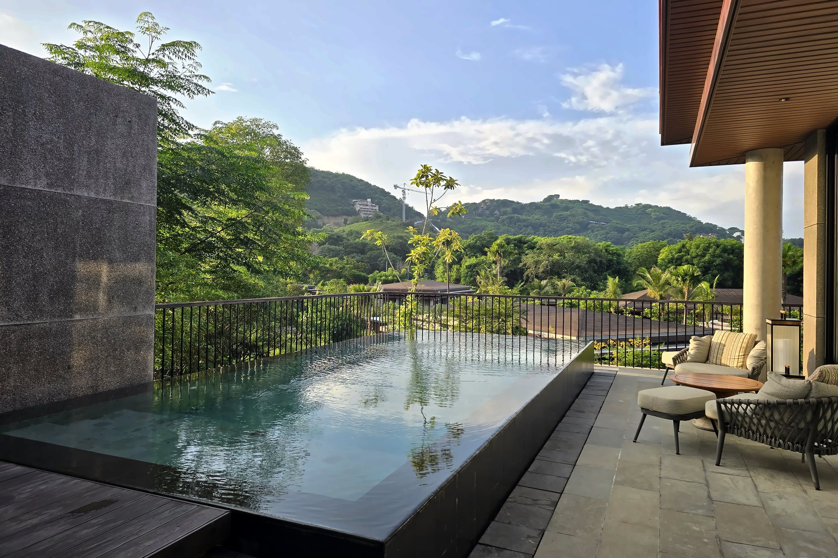 An infinity pool on a terrace looking over green hills and the sea