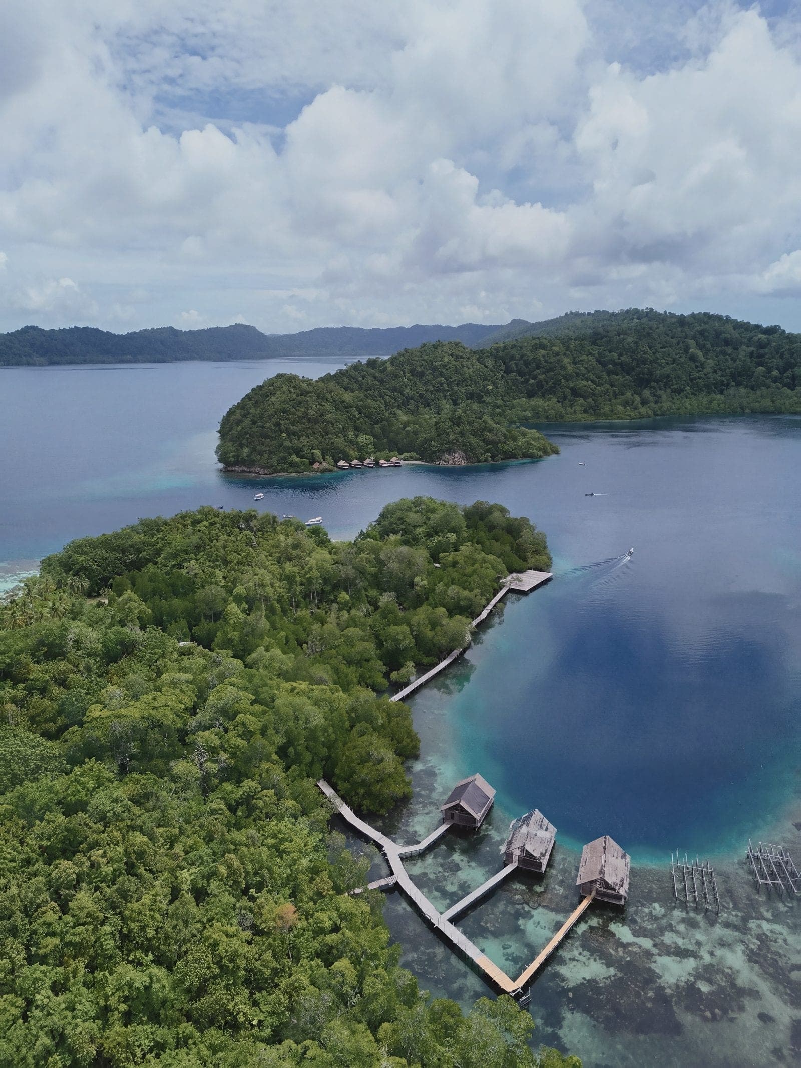 An overwater jetty and lagoon among jungle islands, from above