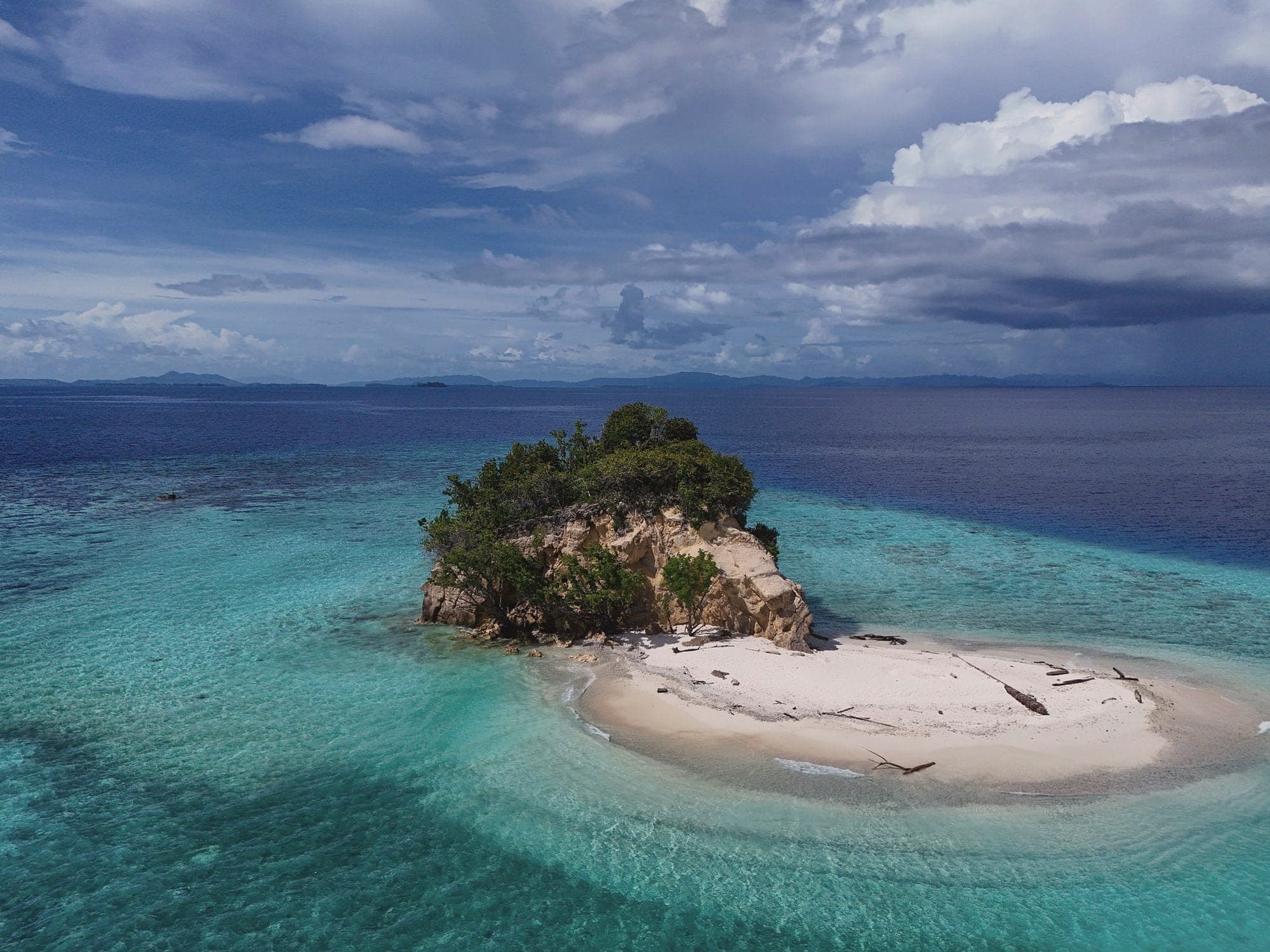 A small rocky islet with a white sandbar ringed by turquoise reef, Raja Ampat