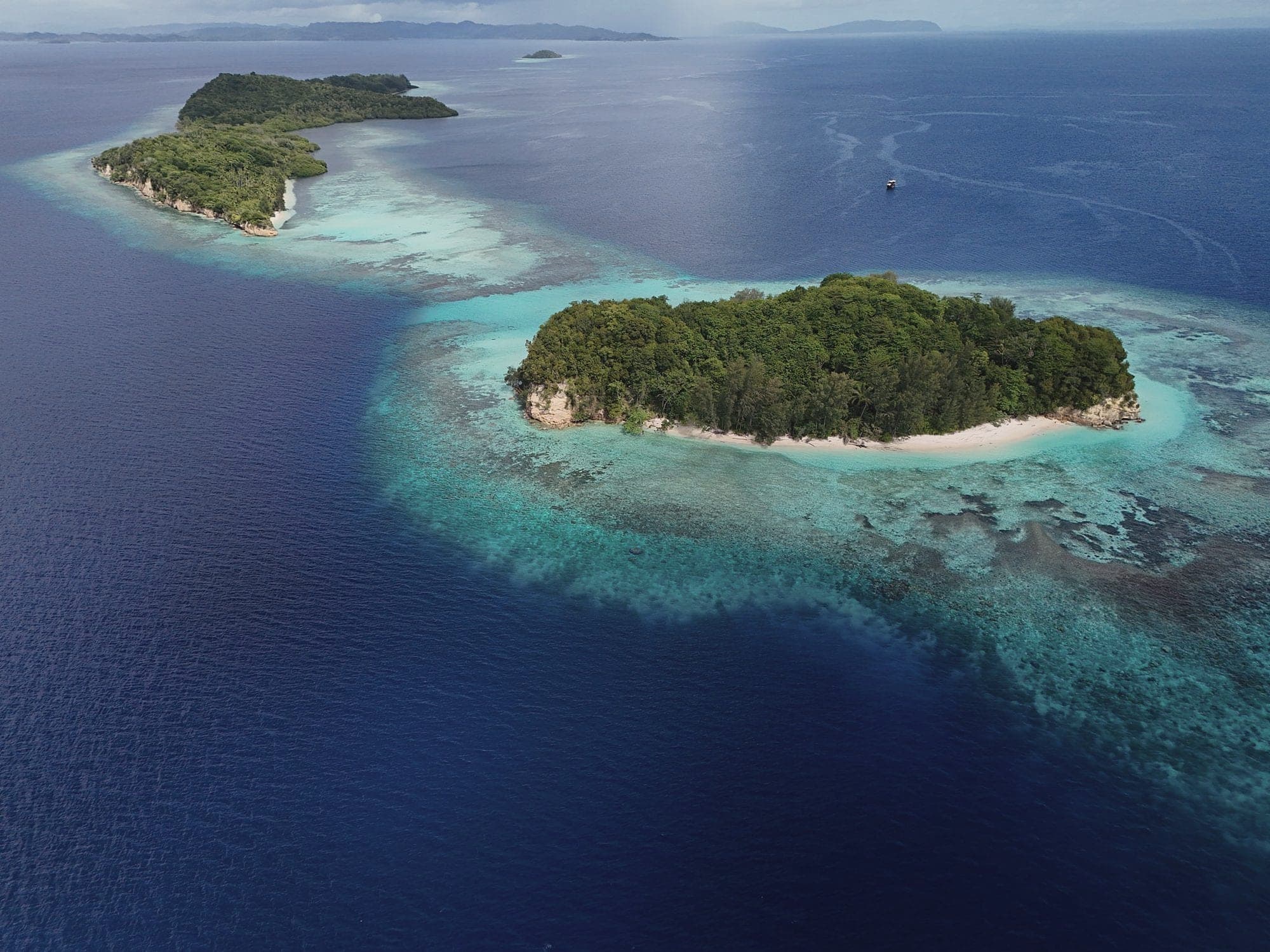 Reef-ringed islets in deep blue water, from the drone
