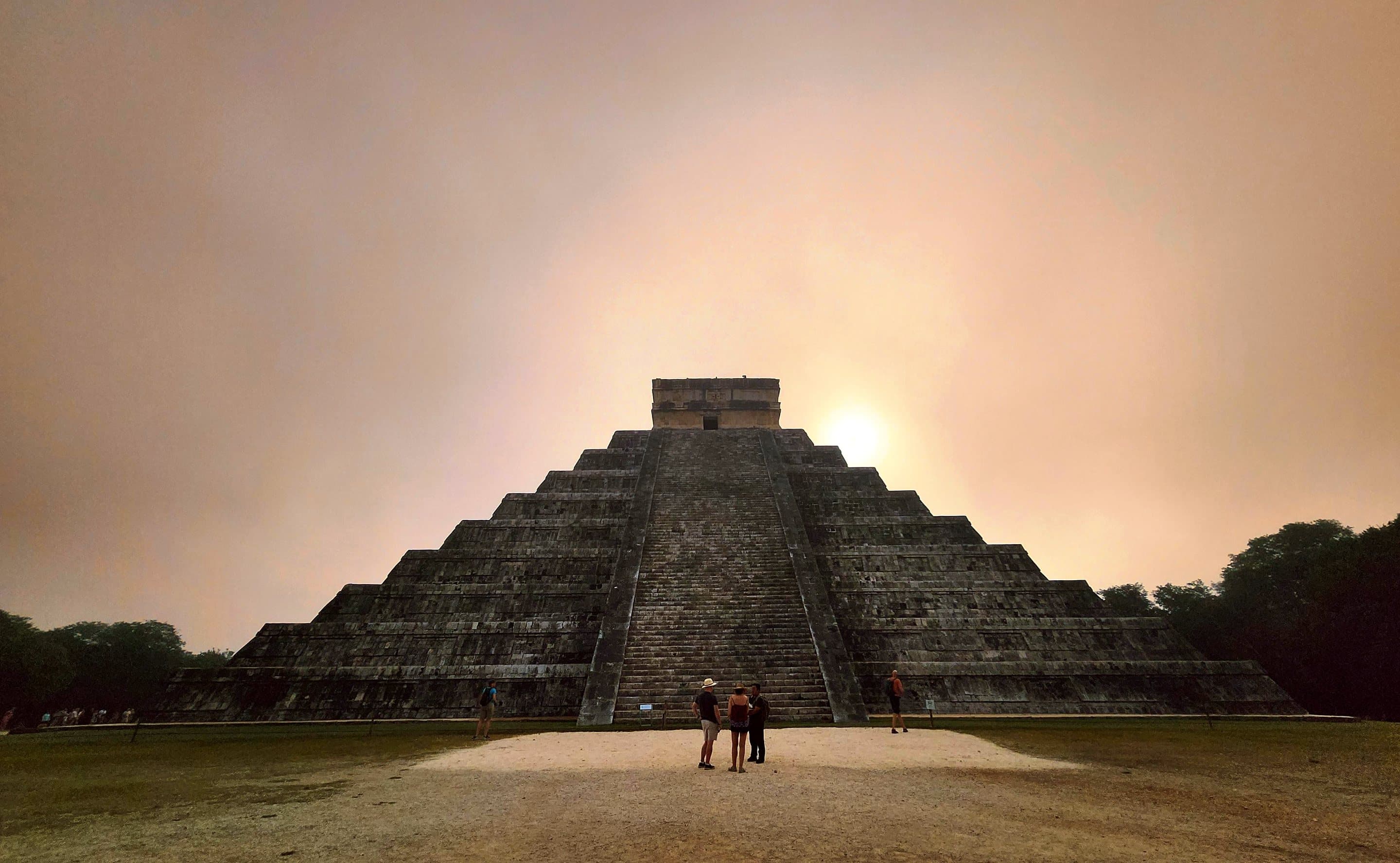 El Castillo at Chichen Itza at dusk, two people small at its base