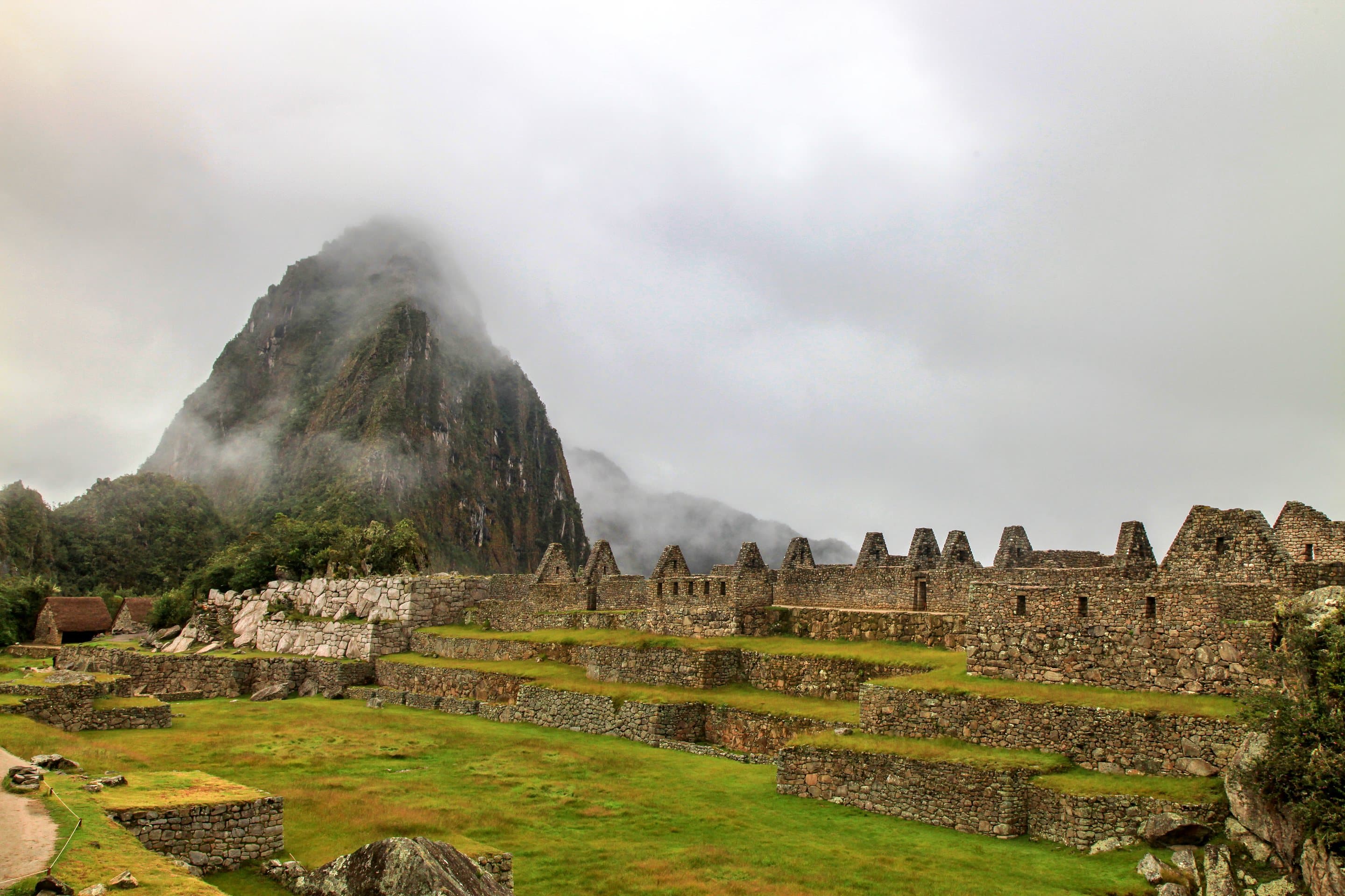 The terraces of Machu Picchu below the green peak of Huayna Picchu, cloud on the ridges