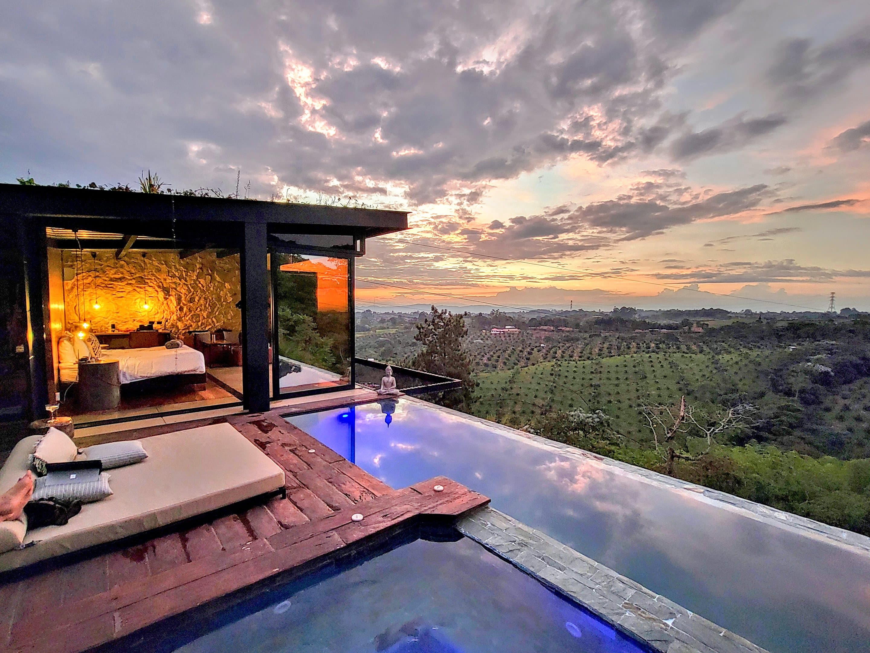 A glass-walled suite with its own infinity pool at sunset, coffee hills beyond